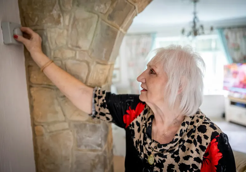 Person adjusting a home thermostat